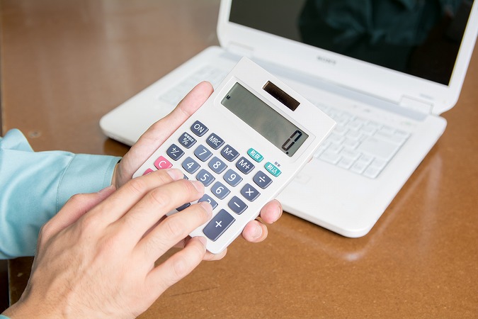 電卓を打つ作業服の男性